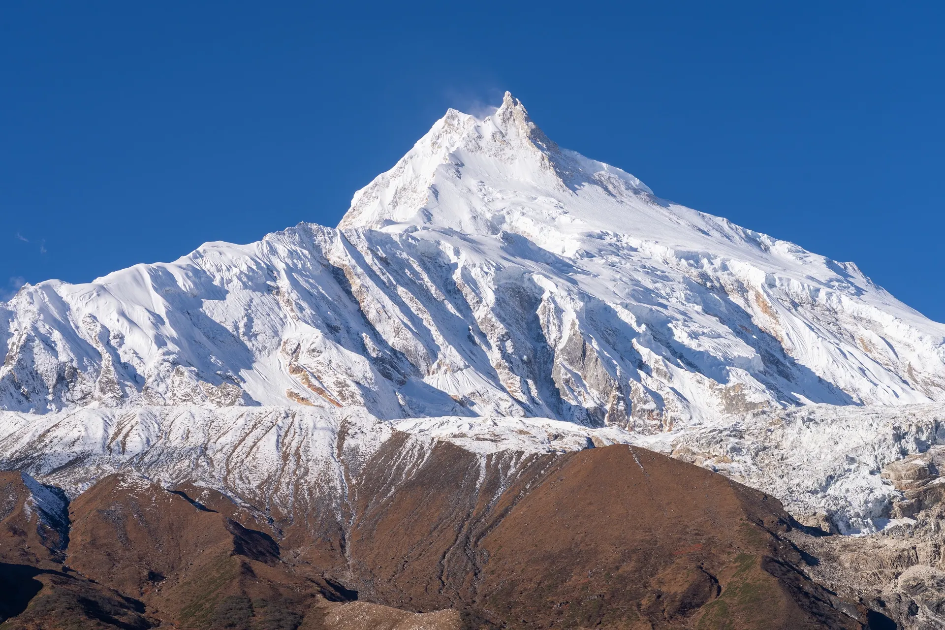 Manaslu's sharp summit against a clear sky, seen from a distance
