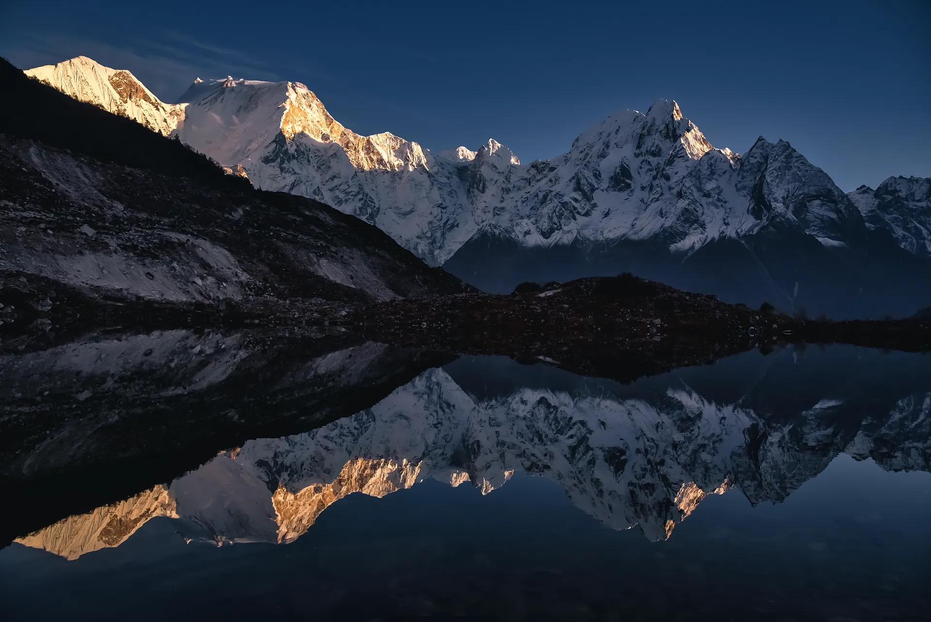 The Manaslu range at dawn, mirrored in a still glacial lake